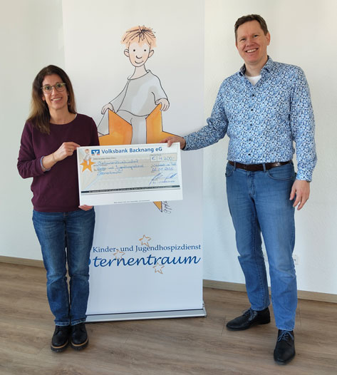 Rotary Club Schorndorf Zwei Personen, eine Frau und ein Mann, halten einen symbolischen Scheck vor einem Banner des Kinder- und Jugendhospizdienst Sternentraum.